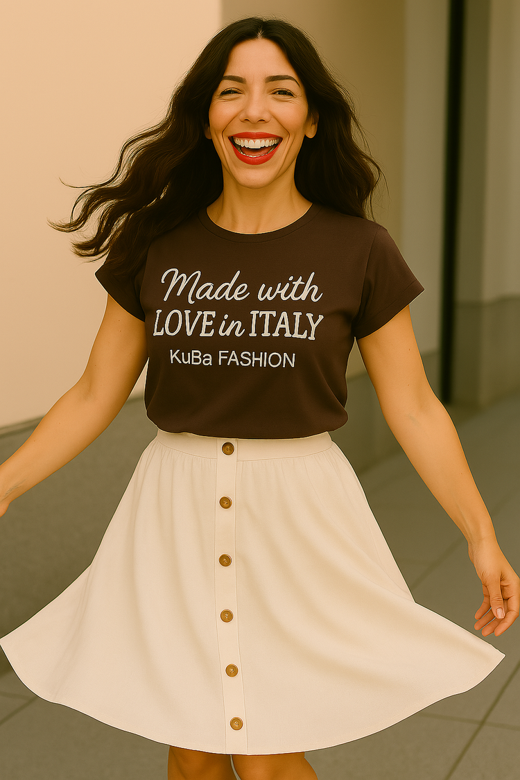 junge frau mit langen dunklen gewellten Haaren ist vergnügt und schwingt ihren weißen Rock. Sie trägt ein T-Shirt mit Aufschrift Made with Love in Italy bei KuBa Fashion