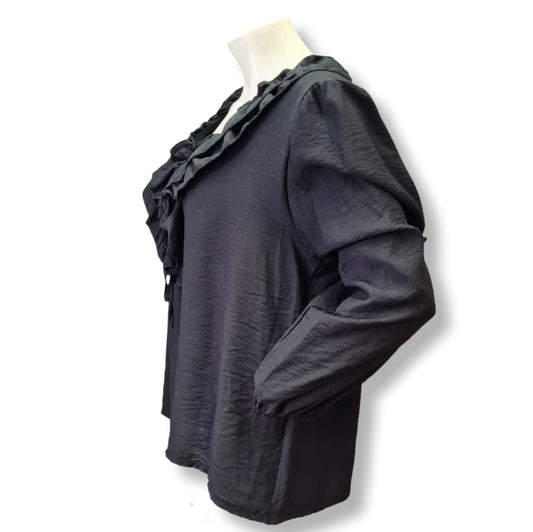 Die Bluse Eva besteht aus 85% Viskose und 15% Nylon und hat einen weiten Schnitt mit Rüschen. Sie bietet einen klassischen Look in zeitlosem Schwarz. Perfekt für jeden Anlass und angenehm zu tragen dank hochwertiger Materialien. Seitenansicht.