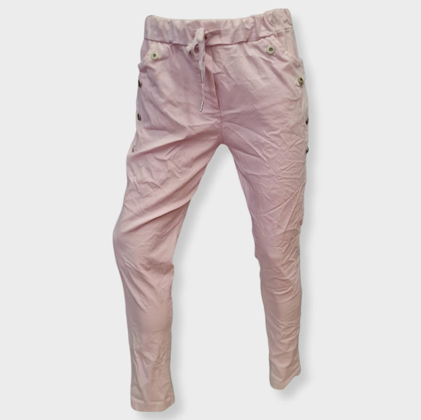 Hose Blanco Rose ist eine sportlich-lässige Hose in der Farbe Rose mit Taschen und verziert mit silbernen Jeansknöpfen. Der breite Gummi Bund mit Kordel sorgt für eine bequeme Passform. Hergestellt aus 76% Viskose, 21% Nylon und 3% Elastan, bietet sie ein angenehmes Tragegefühl. Perfekt für einen lässigen Look mit Stil! Vorderansicht.