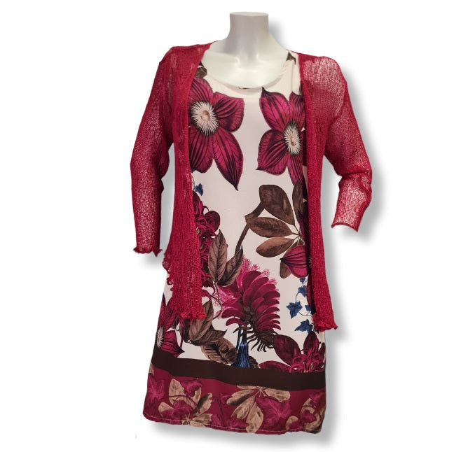 Ein gerade geschnittenes Kleid ohne Ärmel mit einen wunderschönen Druck auf Blumen und Floralen Objekten in den Farben, Beere, Olive und Braun.Hier mit einen roten häckel Bolero.