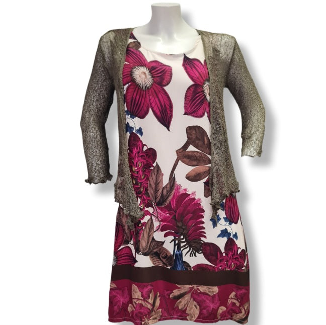 Ein gerade geschnittenes Kleid ohne Ärmel mit einen wunderschönen Druck auf Blumen und Floralen Objekten in den Farben, Beere, Olive und Braun. hier mit einer grünen Häckelweste.