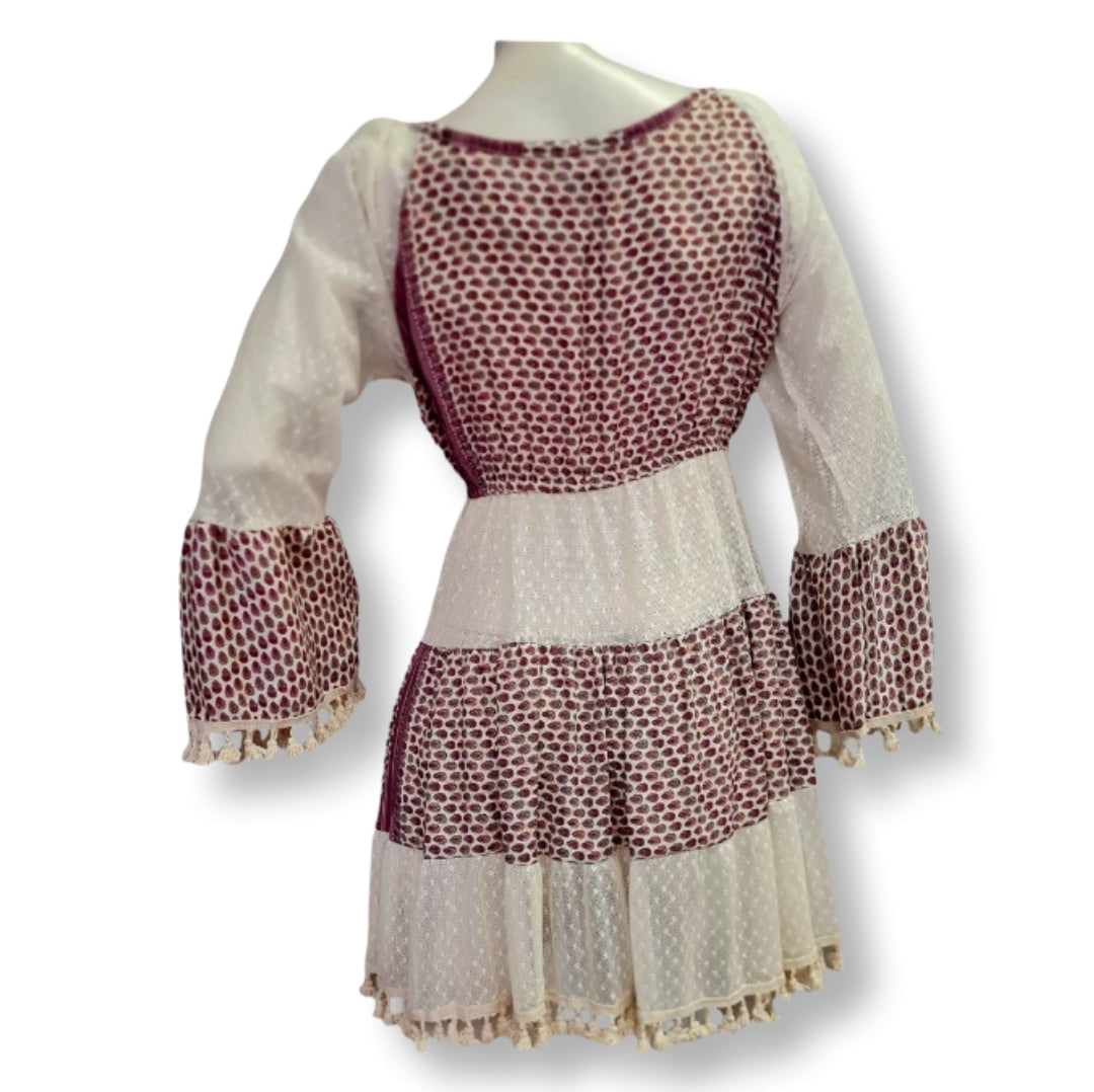 Ein Kleid in Bohostyle in der Farbe Beige und Himbeere. Das Design ist mit mehreren Stoffbahnen und Klöppelarbeiten versehen. In Kurzlänge.