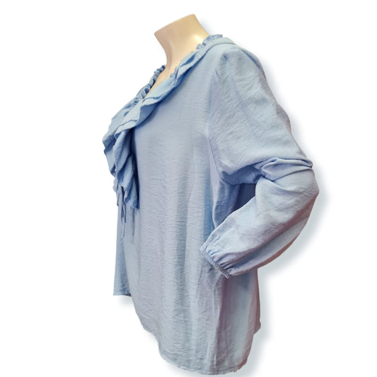 Entdecken Sie die vielseitige Bluse Eva in elegantem Blau. Hergestellt aus 85% Viskose und 15% Elasthan, bietet sie einen angenehmen Tragekomfort und einen weiten Schnitt. Die Rüschen verleihen der Bluse einen femininen Touch. Perfekt für jeden Anlass und leicht zu kombinieren. Seitenansicht.