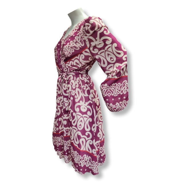 Alice in Beere ein kleid in Wickeloptik. Mit V-Ausschnitt und Gürtel. Der Alloverprintdruck ist in Ornamentenverzierung mit Bordürendruck. Lange Ärmel und Midlänge. 