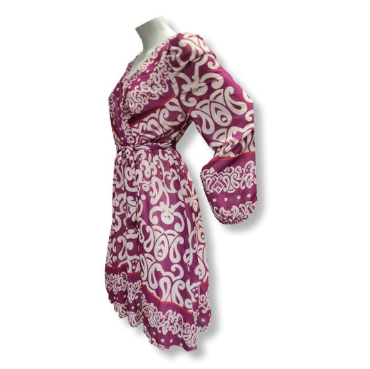 Alice in Beere ein kleid in Wickeloptik. Mit V-Ausschnitt und Gürtel. Der Alloverprintdruck ist in Ornamentenverzierung mit Bordürendruck. Lange Ärmel und Midlänge. 