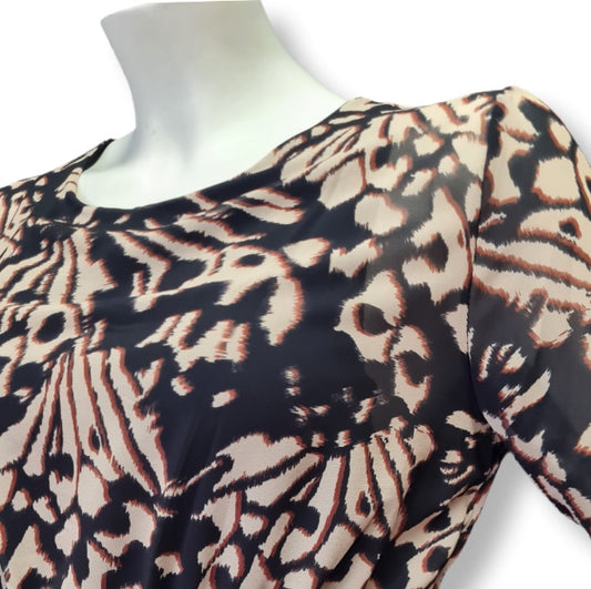 Ein Kleid mit floralen Druckmuster in der Farbe Schoko, Beige, Braun. Rundhals und lange Ärmel. Mit Bordürendruck um Saum und Ämel. 