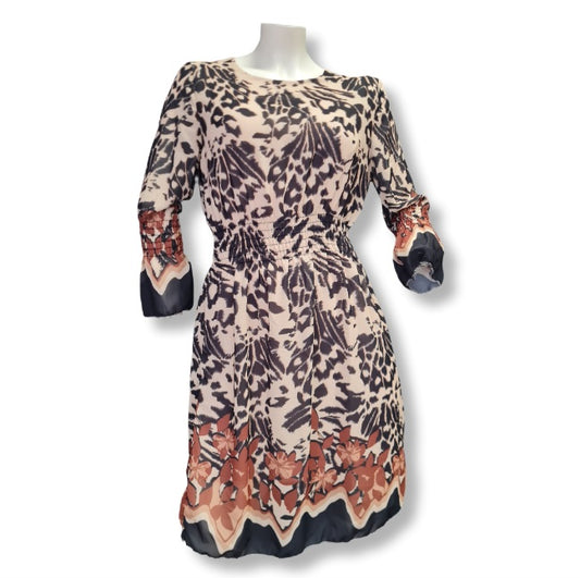 Ein Kleid mit beigen Untergrund darüber Druck in Animal mit Blumendruck. 