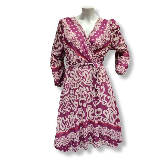 Alice in Beere ein kleid in Wickeloptik. Mit V-Ausschnitt und Gürtel. Der Alloverprintdruck ist in Ornamentenverzierung mit Bordürendruck. Lange Ärmel und Midlänge. 