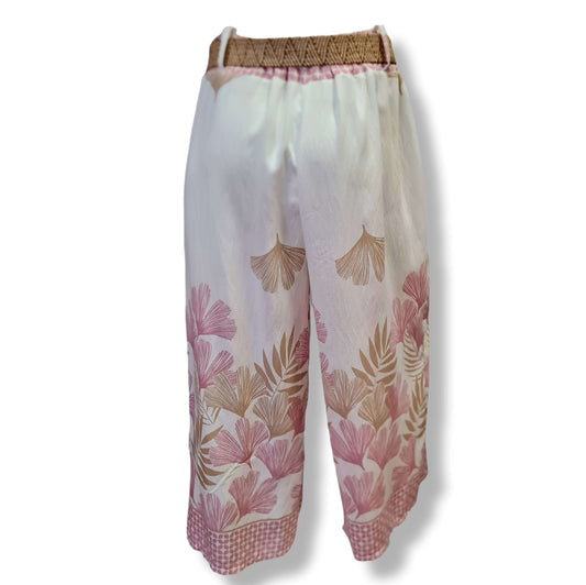 Palazzo Hose in Weiss mit großflächigen Druck auf beiden Beinen mit Motiv Ginkoblatt und Farn. In den Farben Beige und Rosé. Der obere Bereich ist Weiss. Mit Bastgürtel und Gummizug. 