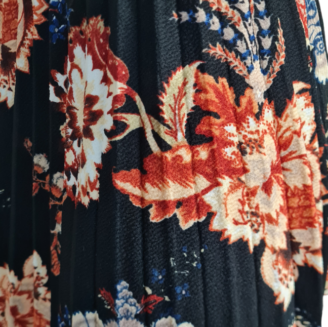 Ein Rock mit plissierung Terrak,ottafarbende Blumen mit Weiss und Blau auf schwarzen Stoff. Mit Gummikbund Knielänge. Seitansicht